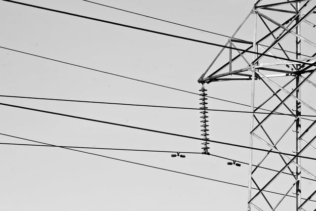 Black-white image of half of a pylon on the right side, with straight powerlines over the rest of the image